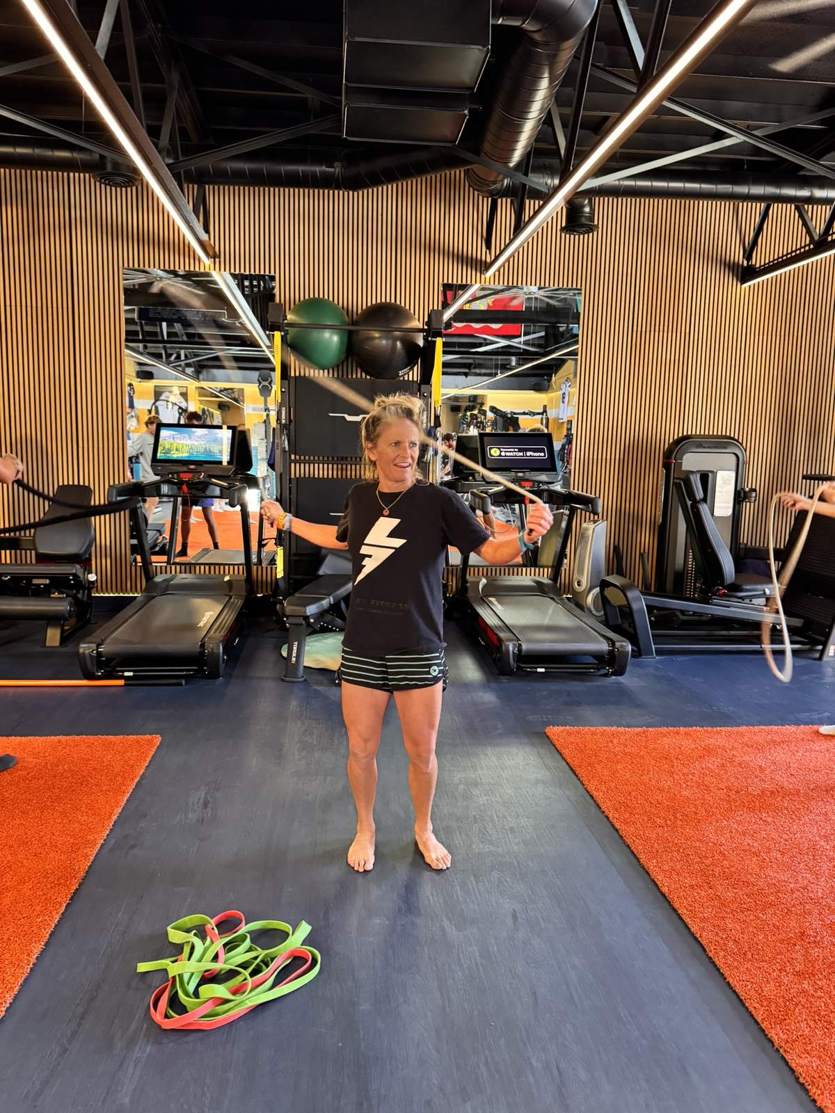 Erika Lilley smiling as she coaches a class, holding a jump rope on the gym floor.